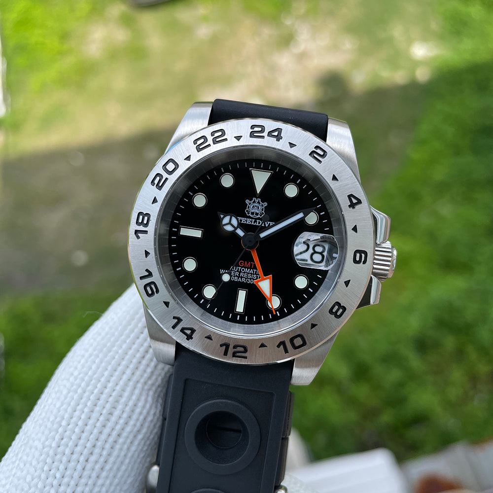 Steeldive SD1992 GMT dive watch on black perforated rubber strap held in hand outdoors