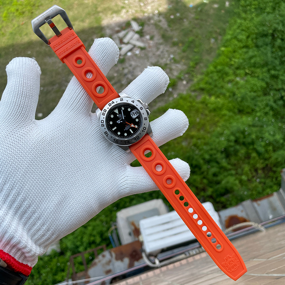 Steeldive SD1992 GMT dive watch with orange perforated rubber strap stretched across a gloved hand