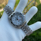 Steeldive SD1993 GMT watch with white dial and black bezel held in gloved hand, lifestyle shot