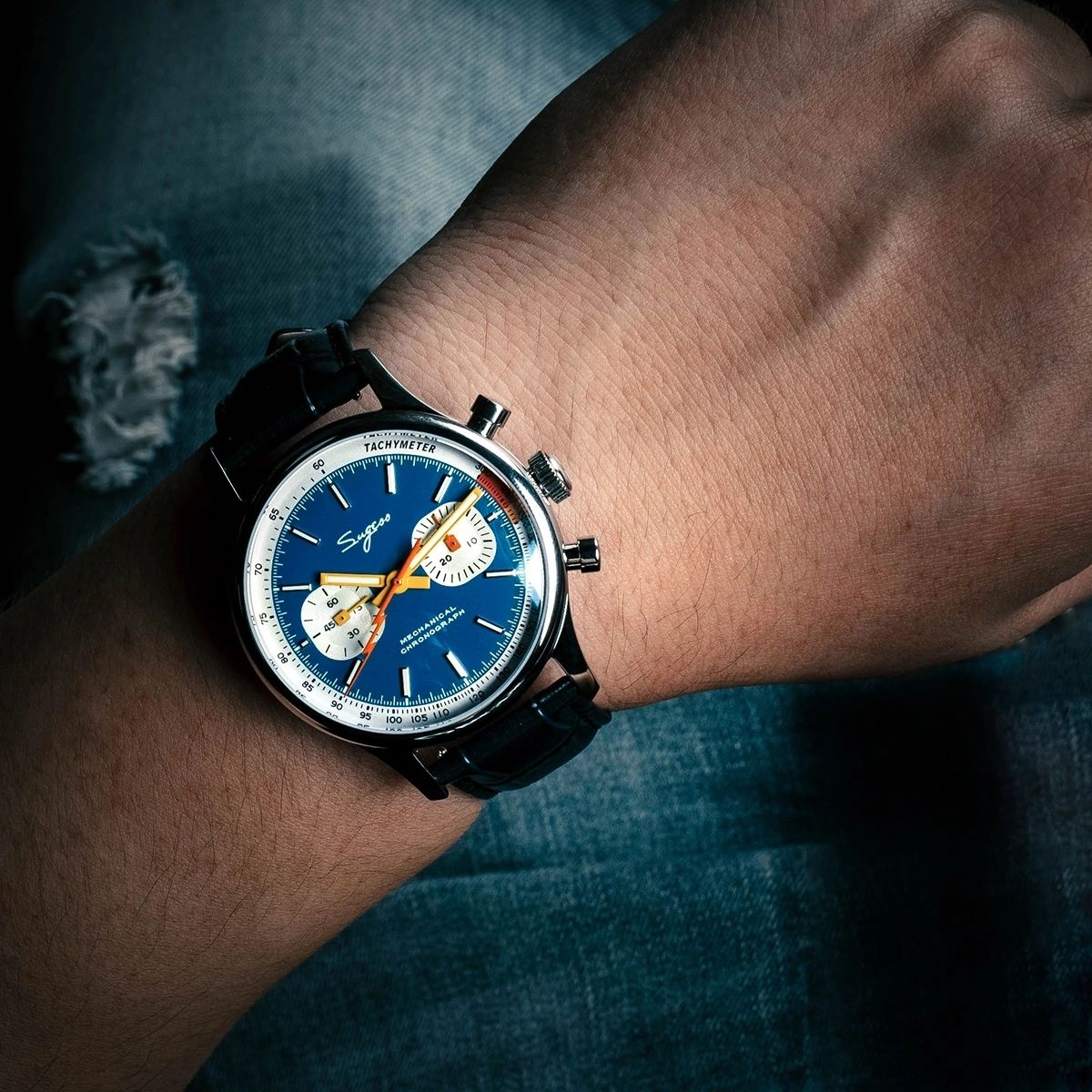 Sugess 387F blue panda chronograph worn on wrist over denim with black leather strap, close-up