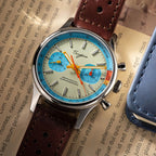 Sugess 387F teal-blue panda chronograph flat-lay on a printed page with brown leather strap