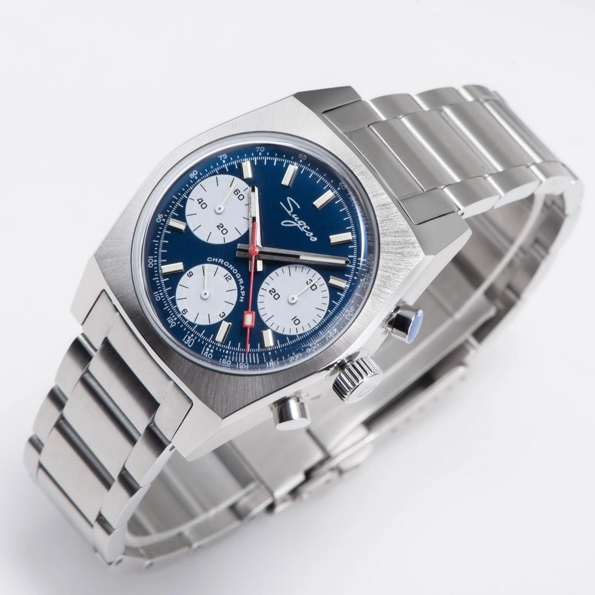 Sugess S419 blue dial, white sub-dials, steel bracelet, angled view resting on a magazine