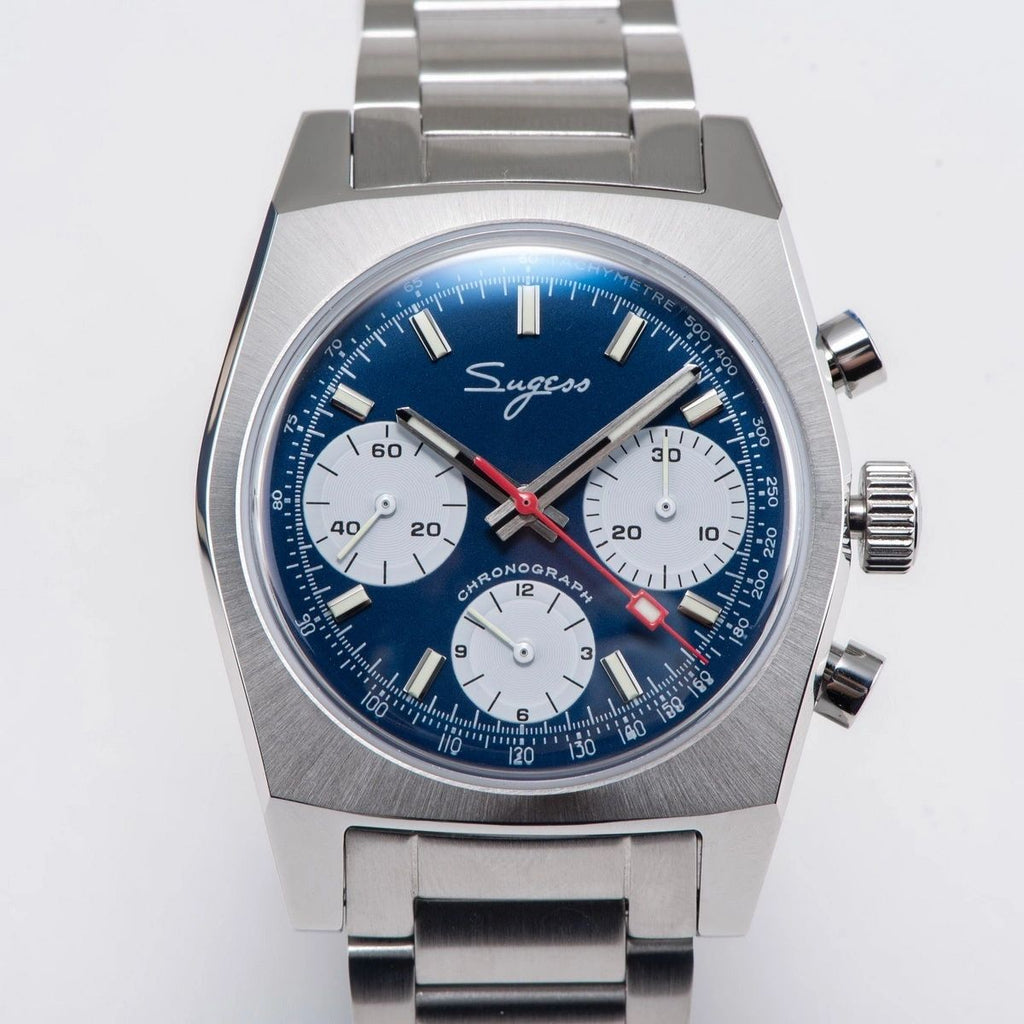 Sugess S419 blue dial, white sub-dials, steel bracelet, angled view on a blue notebook with pen