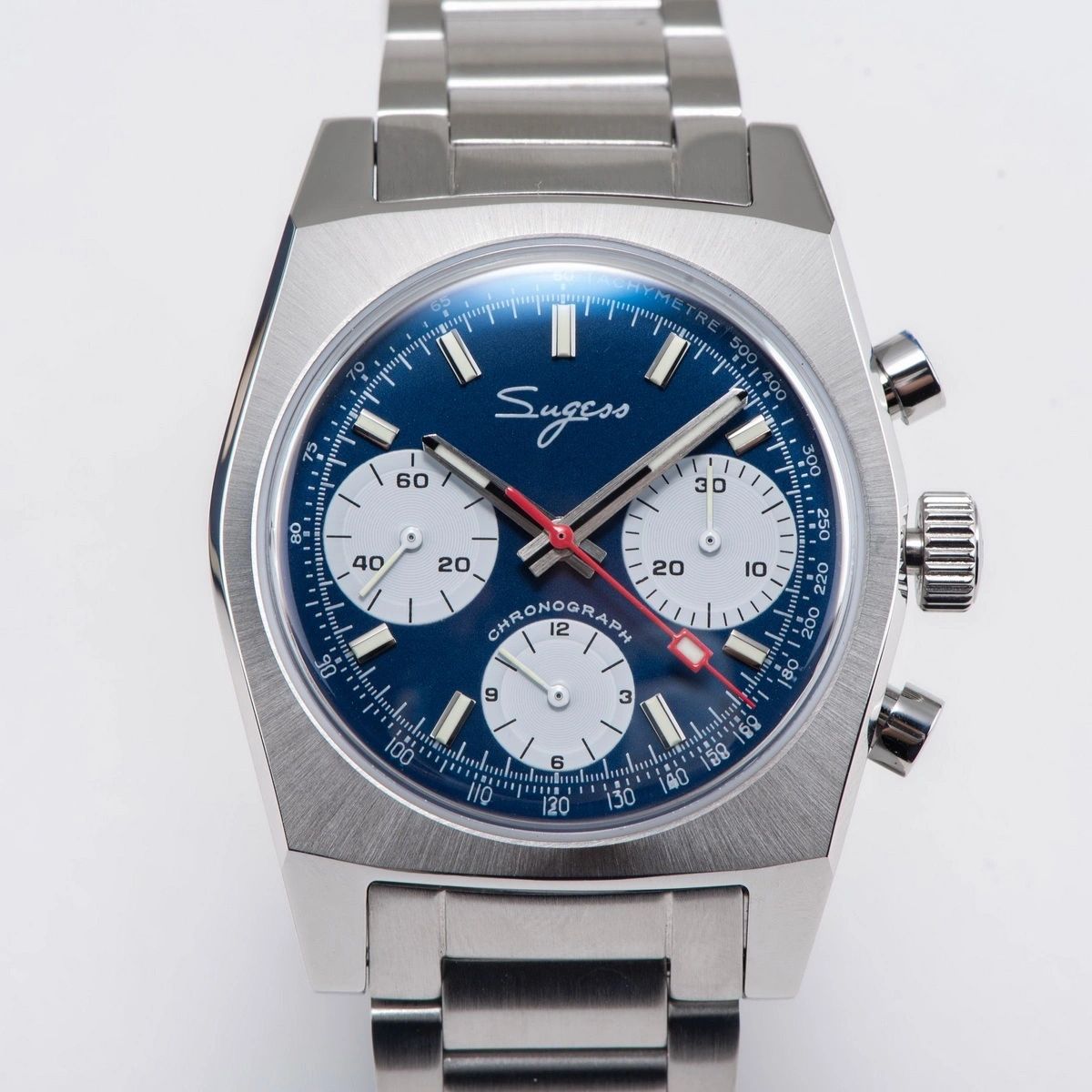 Sugess S419 blue dial, white sub-dials, steel bracelet, angled view on a blue notebook with pen