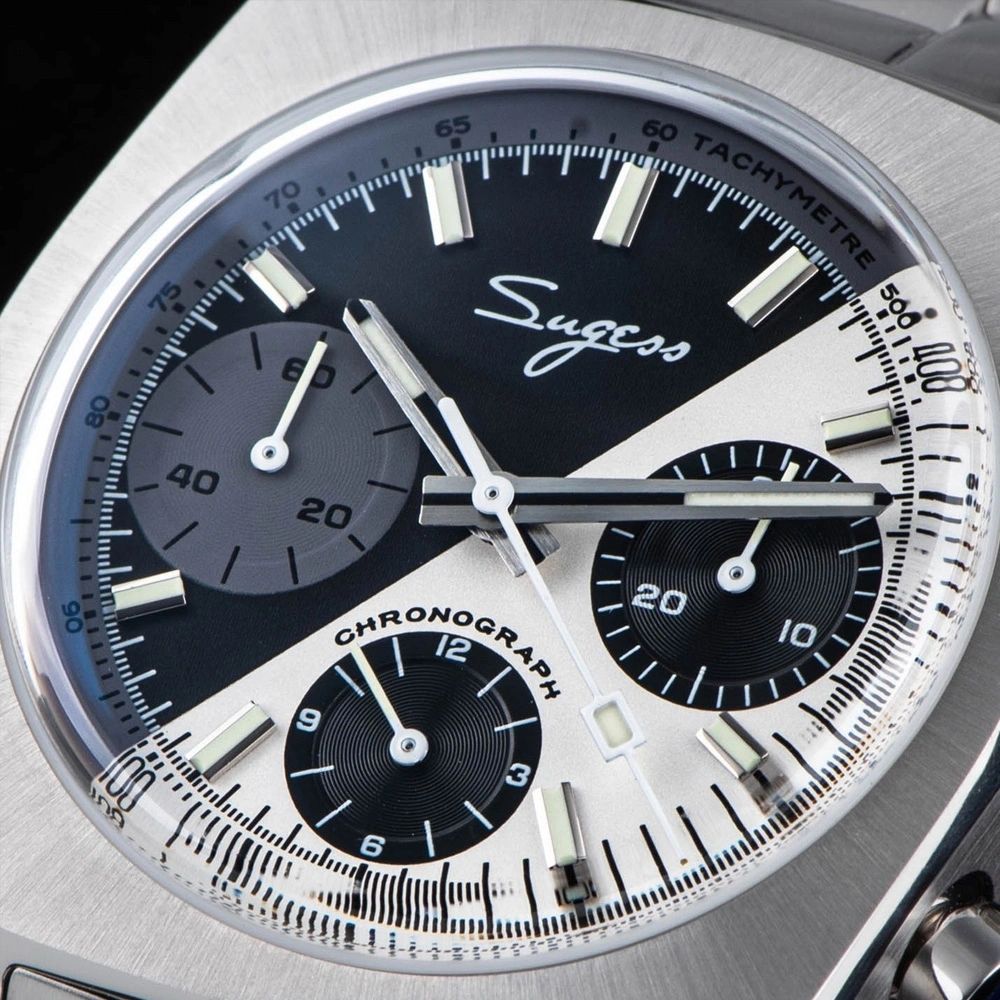 Sugess S419 dual color split black and silver dial on steel bracelet, angled on blue book