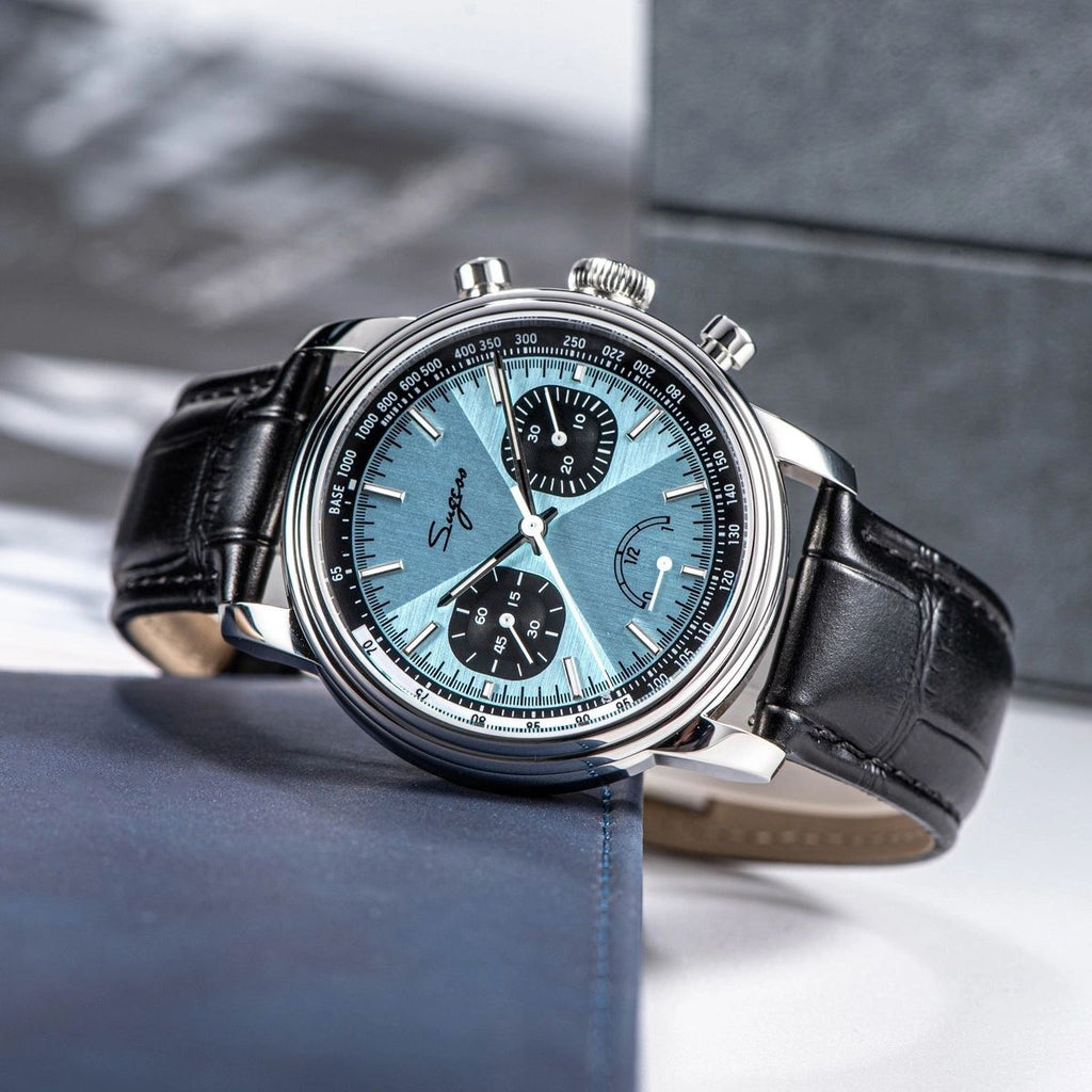 Sugess S438 ice blue chronograph, black sub-dials, black leather strap, angled view beside grey box