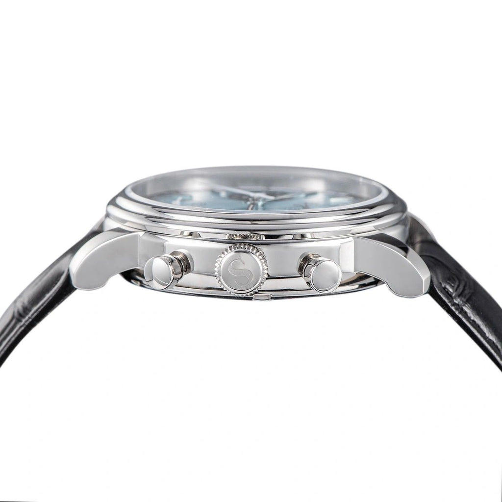 Sugess S438 silver panda chronograph, black sub-dials, racing strap, angled view on blue notebook