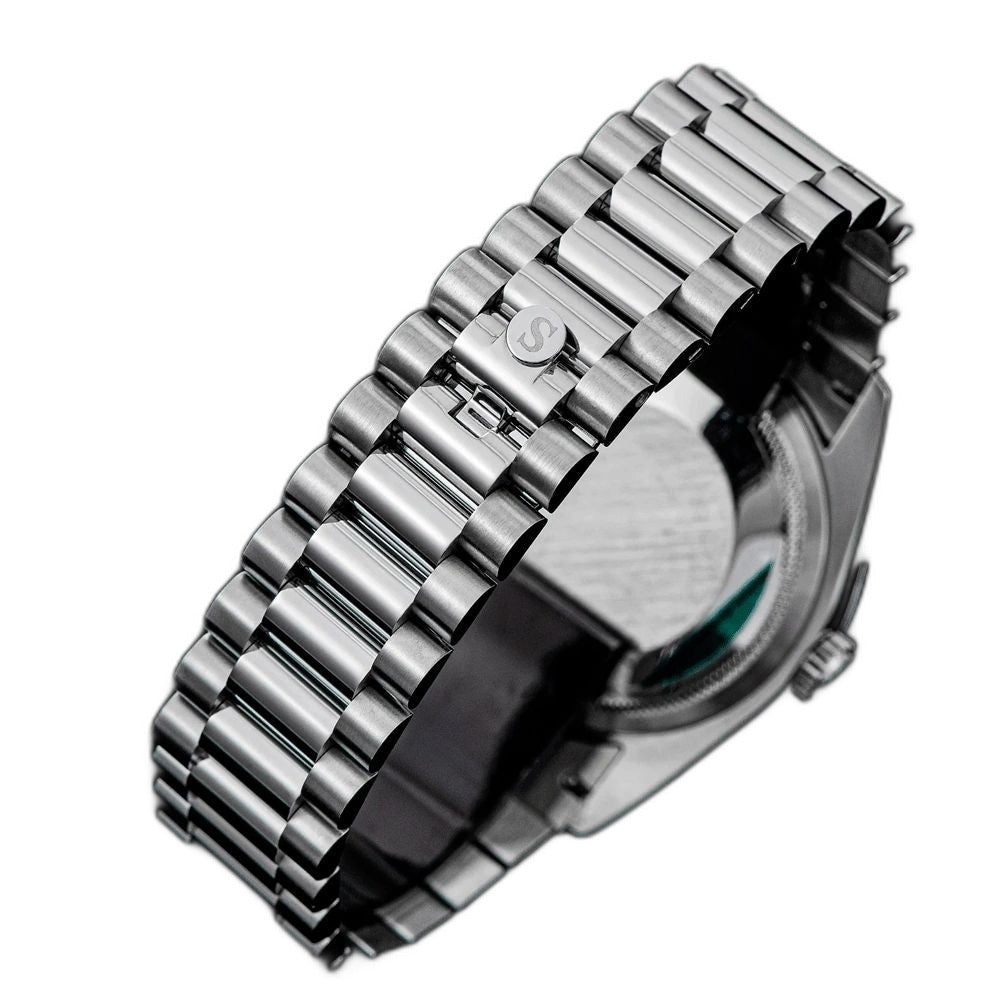 Sugess S449 steel president bracelet with S-engraved clasp and screw-down caseback, angled close-up on black