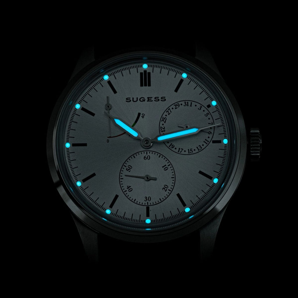 Sugess S458 silver sunburst dial glowing blue lume in the dark, applied markers and hands aglow, close-up