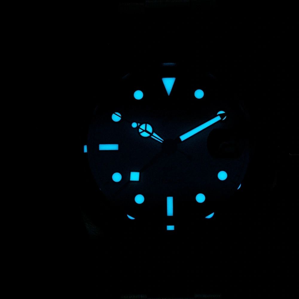 Sugess S463 GMT dial glowing blue lume in the dark, markers, hands and GMT triangle aglow, close-up
