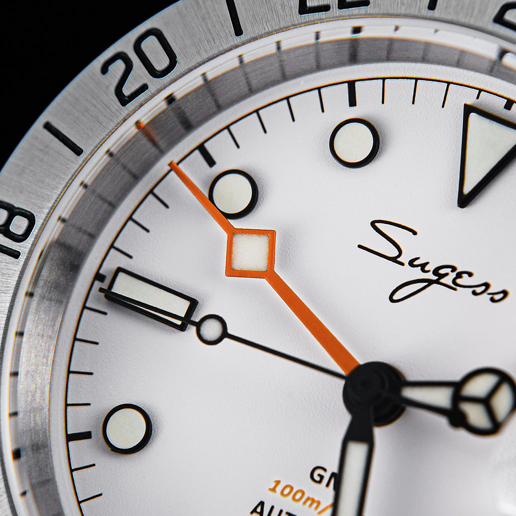 Sugess S463 white dial macro, orange diamond-tip GMT hand, luminous markers and Sugess signature, close-up