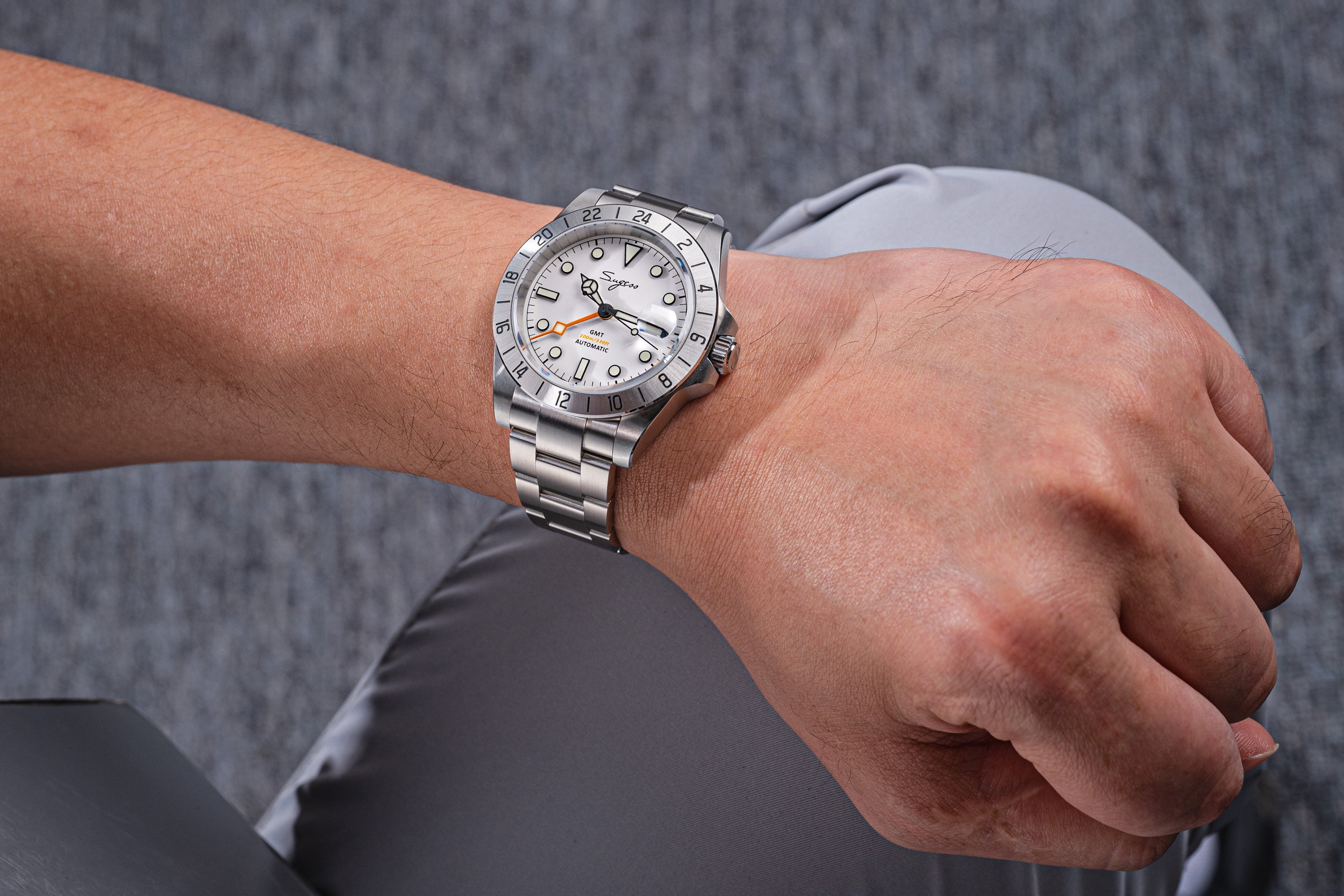 Sugess S463 white-dial GMT automatic watch worn on the wrist, steel bracelet, casual grey setting