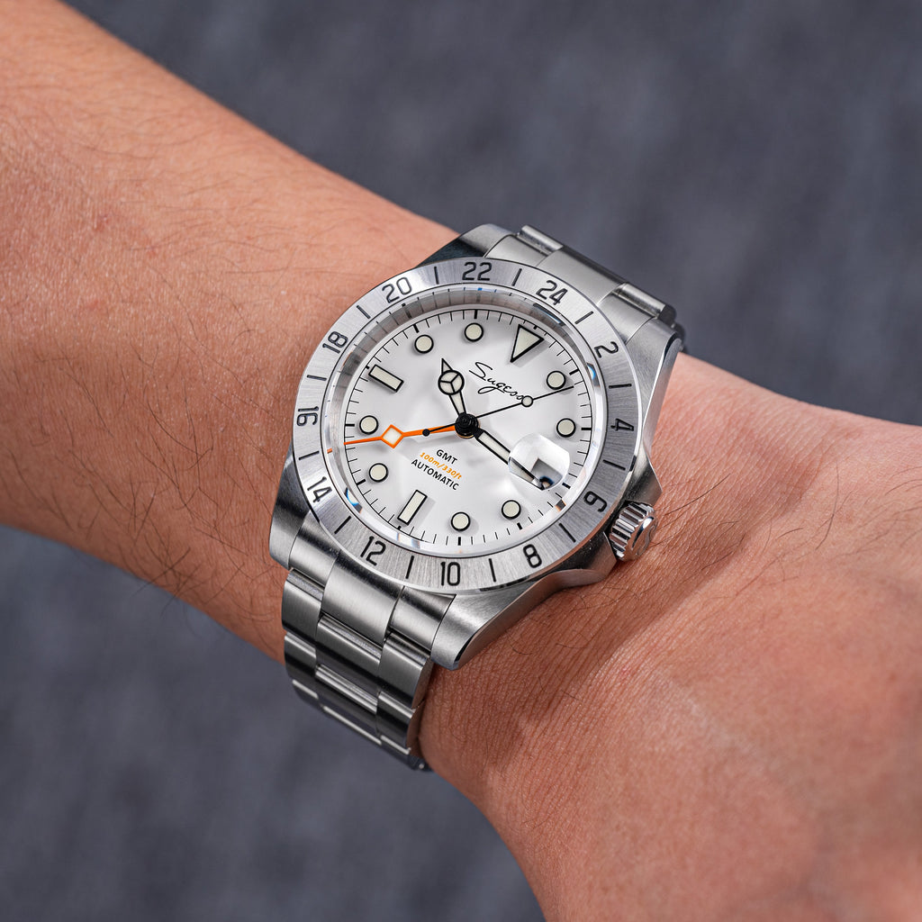 Sugess S463 white-dial GMT automatic watch on the wrist, steel bracelet, angled lifestyle shot in grey