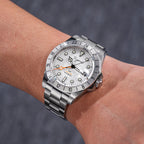 Sugess S463 white-dial GMT automatic watch on the wrist, steel bracelet, angled lifestyle shot in grey