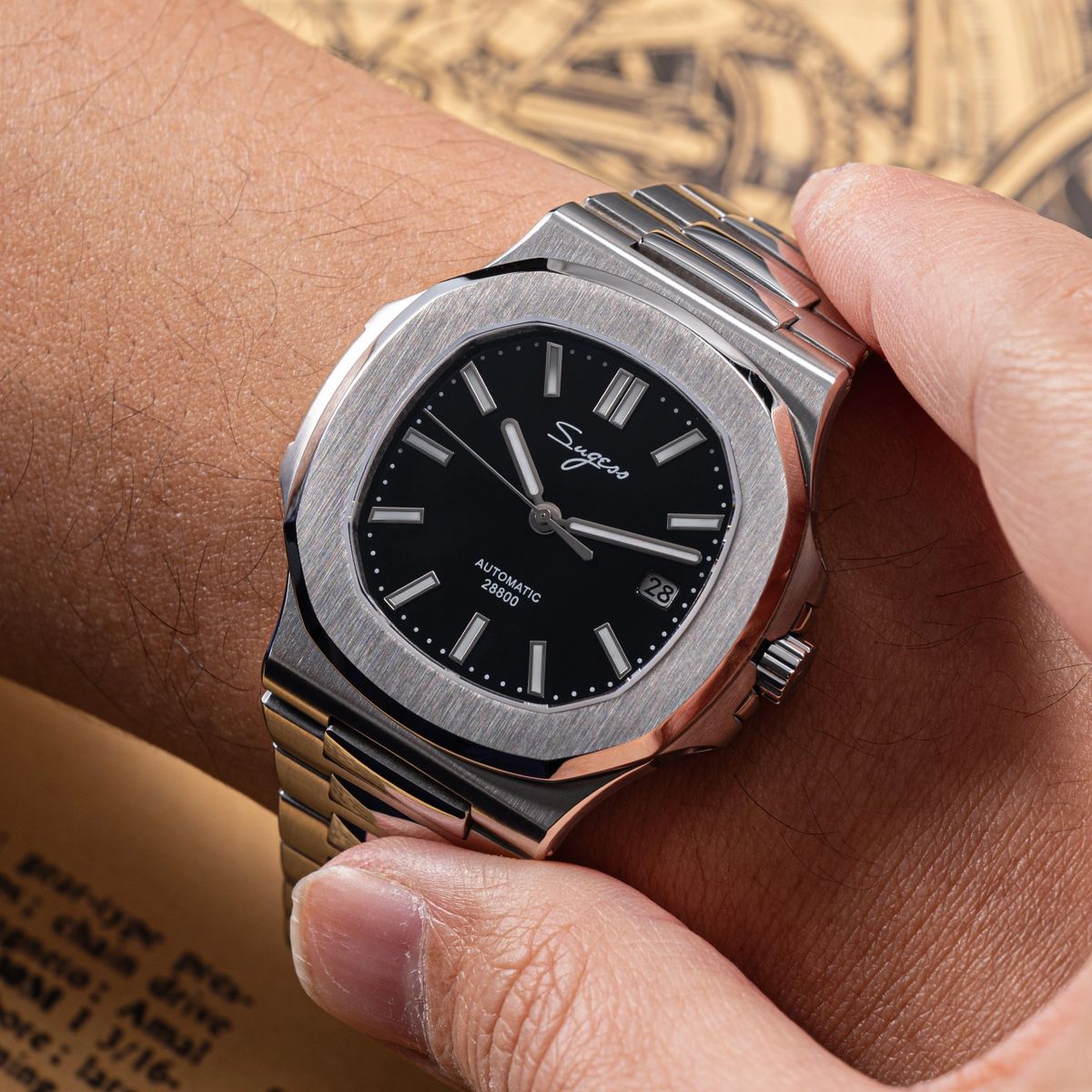 Sugess S466 black dial sport watch held over the wrist, integrated steel bracelet