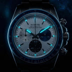 Sugess S473 Chrono Racing silver-white dial glowing teal lume in the dark, markers and hands aglow, close-up